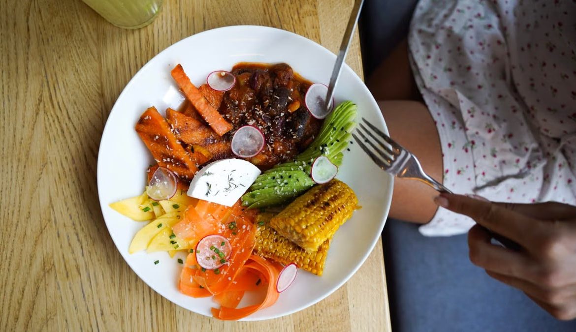 Colorful vegetarian meal with avocado, beans, and corn served on a wooden table. Ideal for healthy lifestyle visuals.