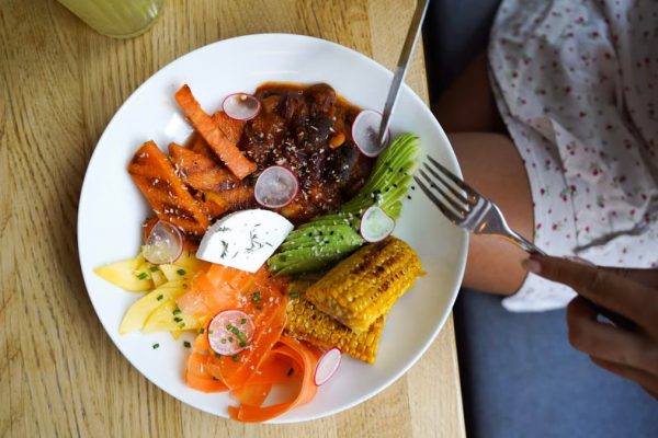 Colorful vegetarian meal with avocado, beans, and corn served on a wooden table. Ideal for healthy lifestyle visuals.