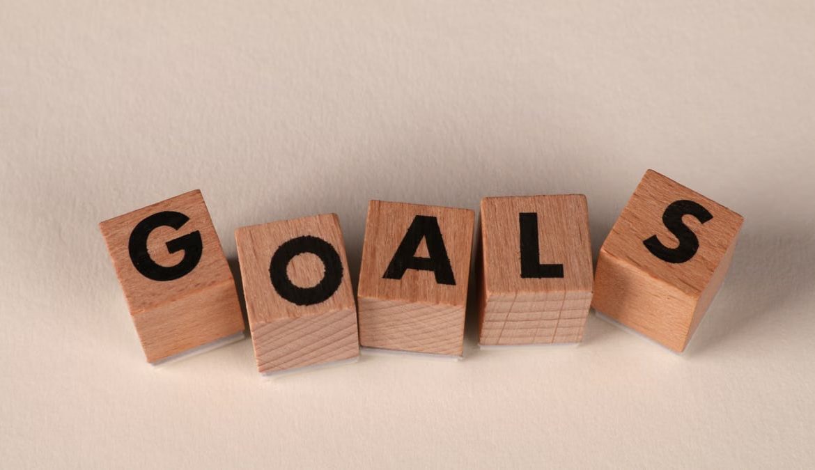 Aligned wooden blocks spelling 'Goals' symbolize target achievement and ambition.